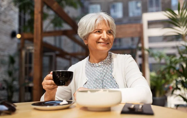 Пожилая женщина пьет кофе в уличном кафе — стоковое фото