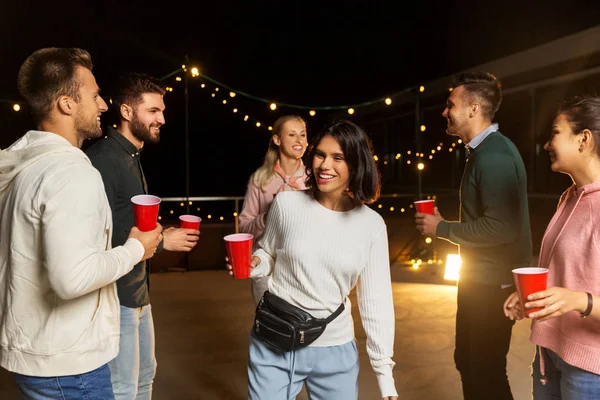 Vrienden met dranken dansen op dak feestje — Stockfoto