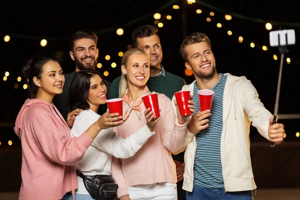 Vänner med drycker tar selfie på taket fest — Stockfoto