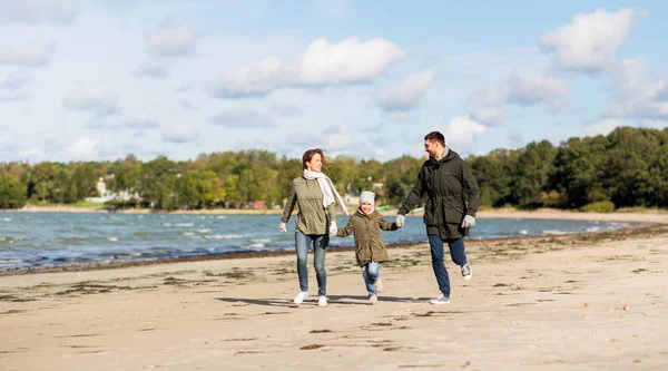 Счастливая семья, бегущая по осеннему пляжу — стоковое фото