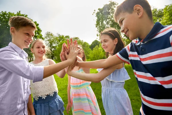 Grupo de niños felices haciendo alta cinco al aire libre — Foto de Stock