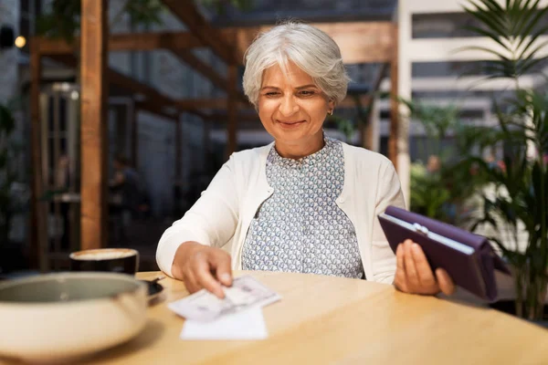 Seniorin mit Geldschein im Café — Stockfoto