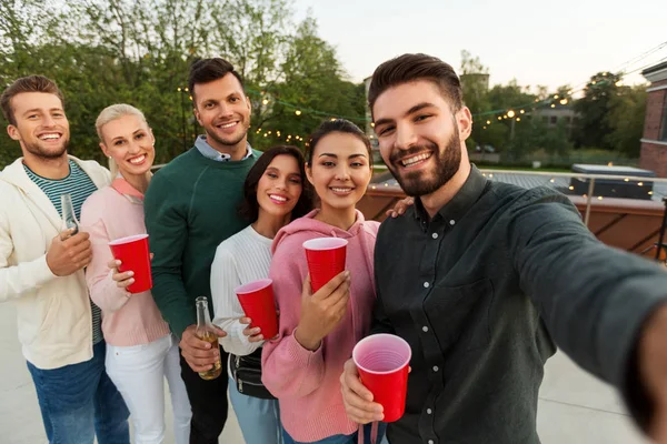 Amigos com bebidas tomando selfie na festa no telhado — Fotografia de Stock