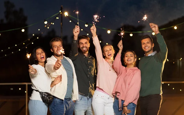 Amigos felices con bengalas en la fiesta en la azotea — Foto de Stock