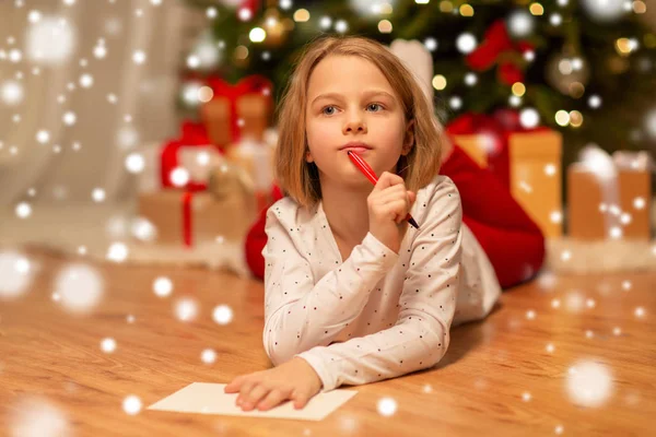 Chica escribiendo la lista de deseos de Navidad en casa —  Fotos de Stock