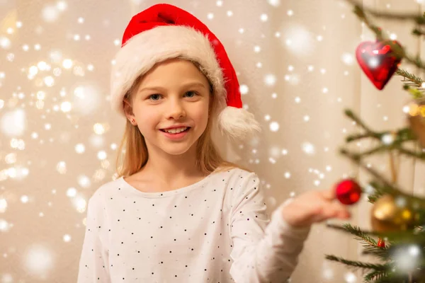 圣诞老人帽子装饰圣诞树的快乐女孩 — 图库照片