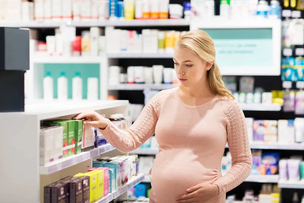 Gelukkig zwangere vrouw met medicatie bij apotheek — Stockfoto