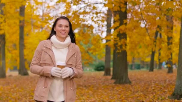 Frau trinkt Kaffee zum Mitnehmen im Herbstpark — Stockvideo