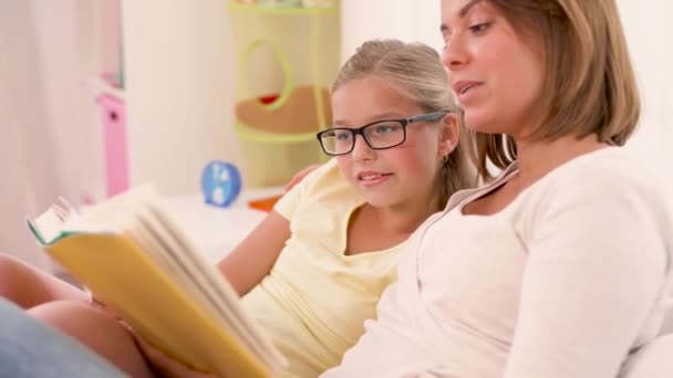 Chica feliz con madre leyendo libro en casa — Vídeos de Stock