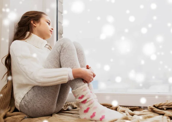 Trauriges Mädchen sitzt im Winter auf Fensterbank zu Hause — Stockfoto