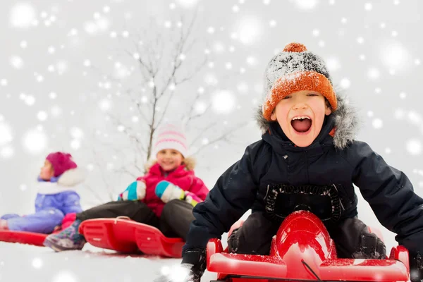 Enfants heureux glissant sur des traîneaux en hiver — Photo
