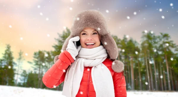 Mujer llamando en el teléfono inteligente sobre bosque de invierno — Foto de Stock