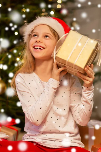 Улыбающаяся девушка в шляпе Санты с рождественским подарком — стоковое фото