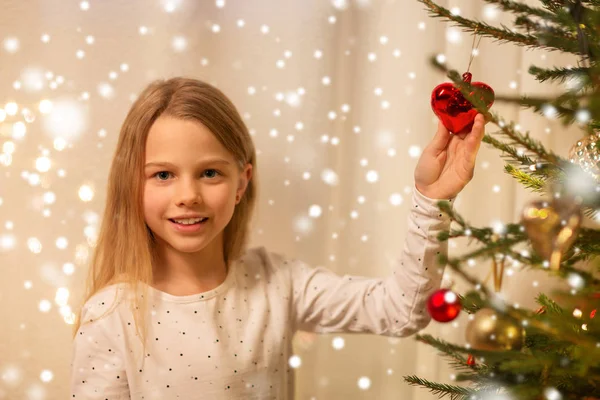 Happy girl in red dress decorating christmas tree — Stock Photo, Image