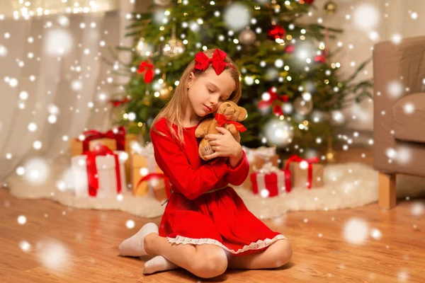 Evde oyuncak ayı sarılma kırmızı elbiseli kız — Stok fotoğraf