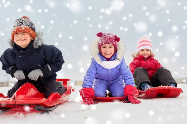 Niños pequeños felices deslizándose hacia abajo en trineos en invierno —  Fotos de Stock