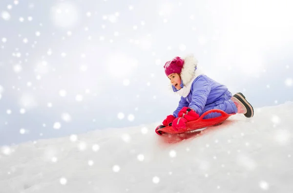 Chica deslizándose hacia abajo en platillo de nieve trineo en invierno — Foto de Stock
