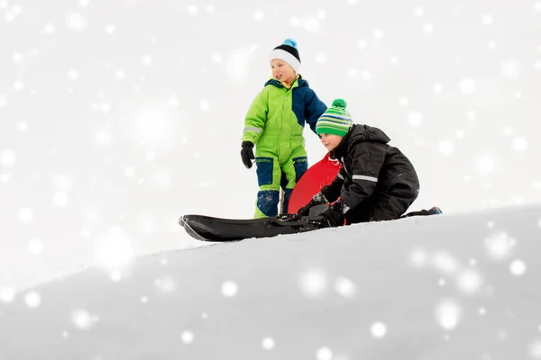 Kinderen glijden op sleeën bergafwaarts sneeuw in de winter — Stockfoto