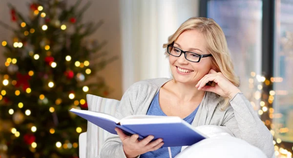 Wanita dalam kacamata membaca buku pada hari Natal — Stok Foto