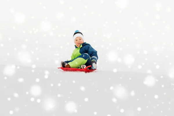 Heureux garçon glissant sur traîneau descendant neige colline en hiver — Photo