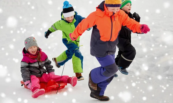 愉快的孩子与雪橇有乐趣在室外在冬天 — 图库照片