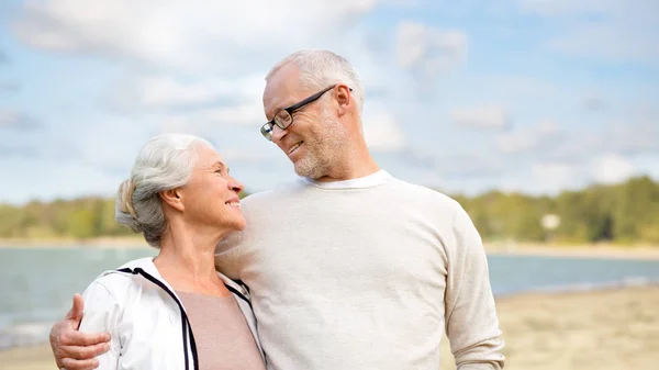 Glückliches älteres Paar, das sich über dem Strand umarmt — Stockfoto