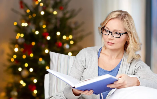 Frau mit Brille liest Buch über Weihnachten — Stockfoto