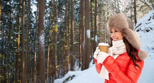 Mulher em chapéu de pele com café sobre floresta de inverno — Fotografia de Stock