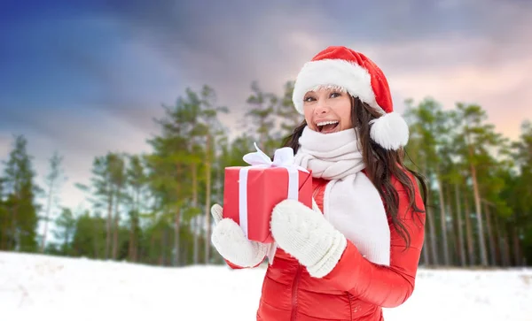 Szczęśliwa kobieta w kapeluszu Mikołaja z prezentem świątecznym — Zdjęcie stockowe