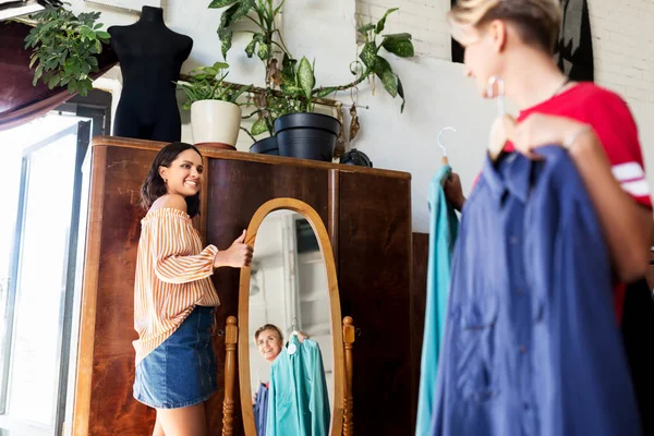 Mujeres eligiendo ropa en la tienda de ropa vintage —  Fotos de Stock