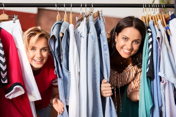 Женщины веселятся на вешалке магазина винтажной одежды — стоковое фото