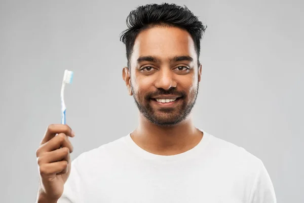 灰色の背景の上に歯ブラシを持つインド人 — ストック写真