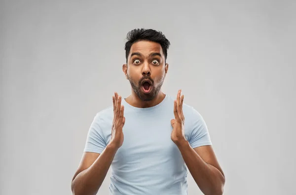 scared man in t-shirt over grey background