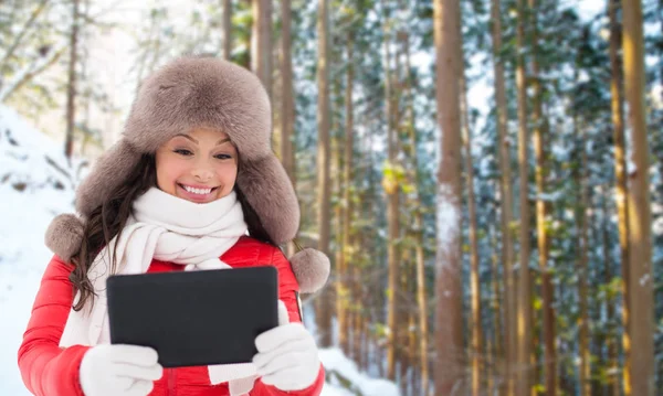 Žena v kožešinovou čepici s tablet pc přes zimní les — Stock fotografie