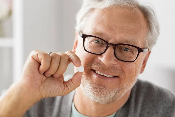 Feliz hombre mayor sosteniendo blanco píldora redonda — Foto de Stock