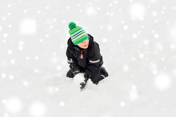 Heureux petit garçon jouer avec la neige en hiver — Photo