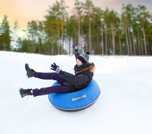 Szczęśliwy młody człowiek, przesuwając w dół wzgórza na snow tube — Zdjęcie stockowe