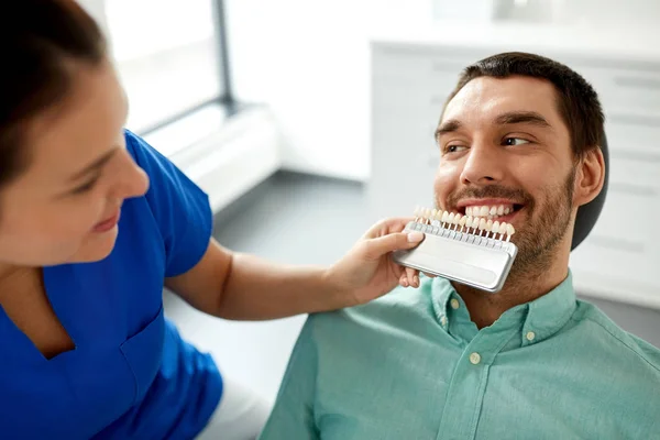 Tandarts kiezen van de kleur van de tand voor patiënt bij kliniek — Stockfoto