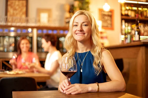 Glückliche Frau trinkt Rotwein in Bar oder Restaurant — Stockfoto