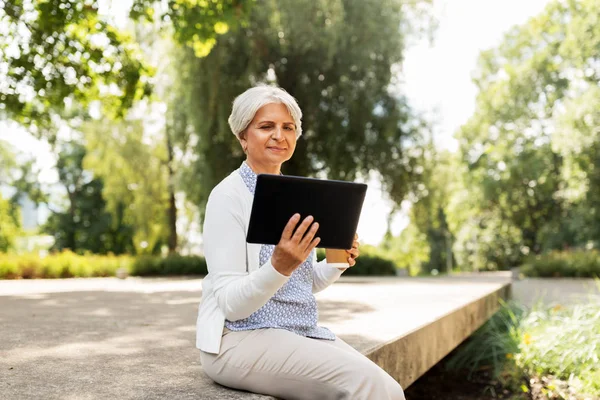 Stara kobieta z komputera typu tablet i kawa w lato park — Zdjęcie stockowe