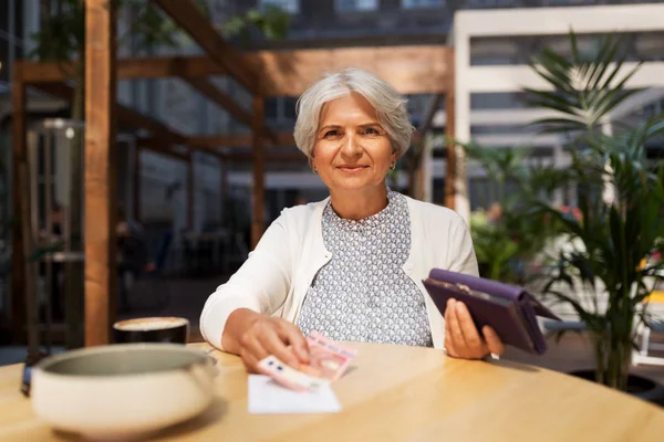 Seniorin mit Geldschein im Café — Stockfoto