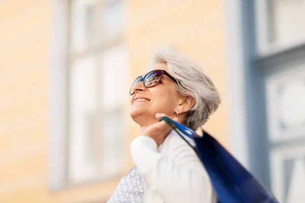 Пожилая женщина в солнцезащитных очках с пакетами — стоковое фото