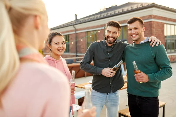 Amici felici con bevande che si abbracciano alla festa sul tetto — Foto Stock