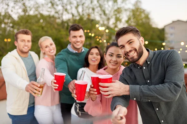 Vänner med drycker tar selfie på taket fest — Stockfoto