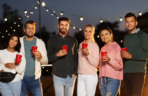 Vänner med part koppar på taket på natten — Stockfoto