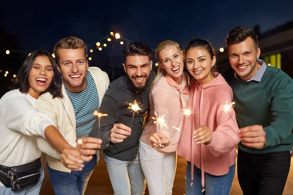 Amigos felices con bengalas en la fiesta en la azotea — Foto de Stock