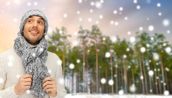 Uomo sorridente in cappello e sciarpa sopra foresta invernale — Foto Stock