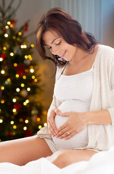 Mujer embarazada haciendo gesto de corazón en Navidad —  Fotos de Stock