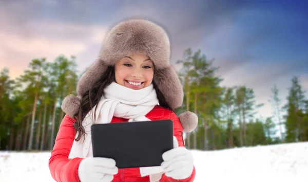 Vrouw in bont muts met tablet-pc over winter forest — Stockfoto