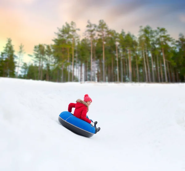 Счастливая девочка-подросток скользит с холма по снежной трубе — стоковое фото